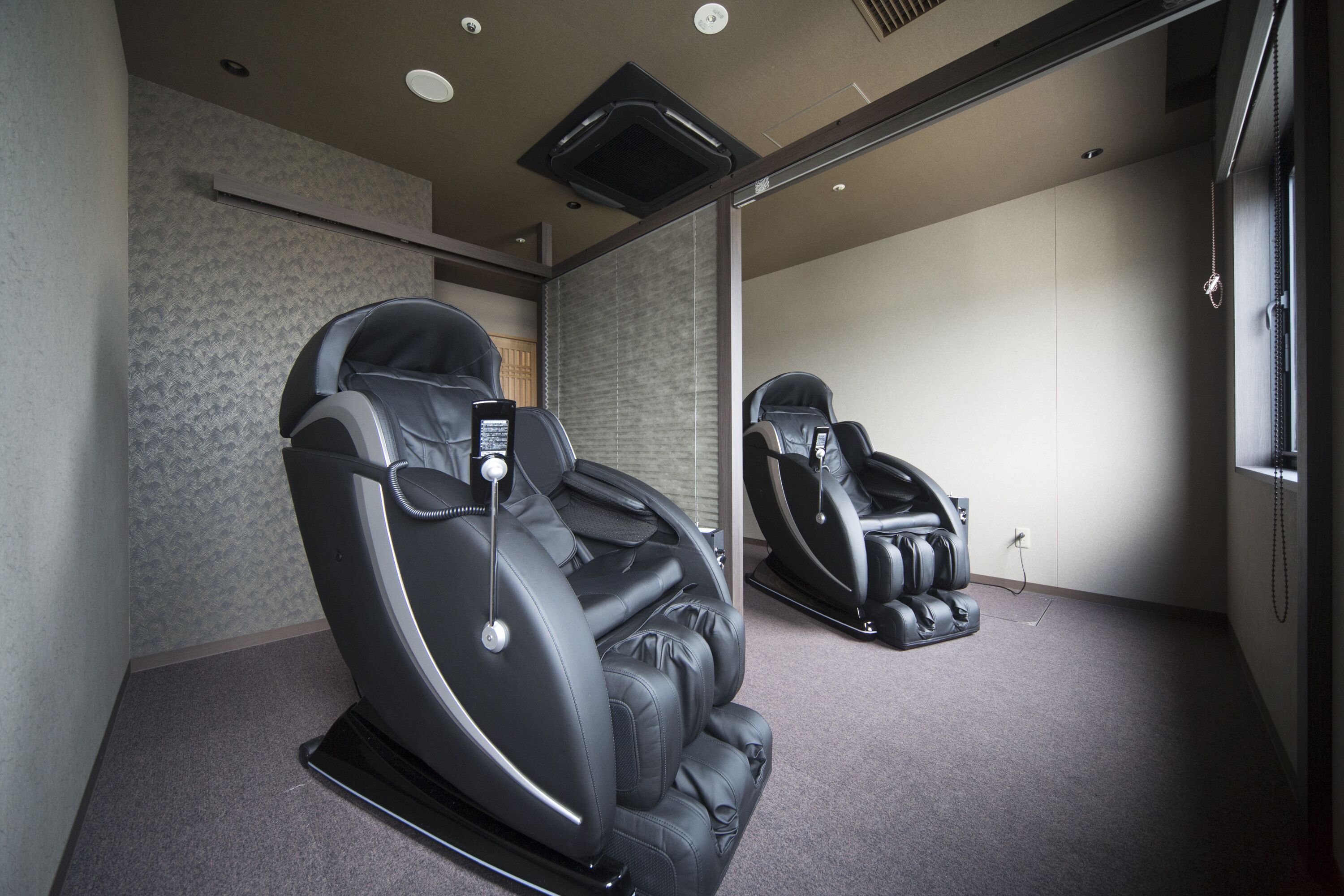 A room with two massage chairs and a large mirror.