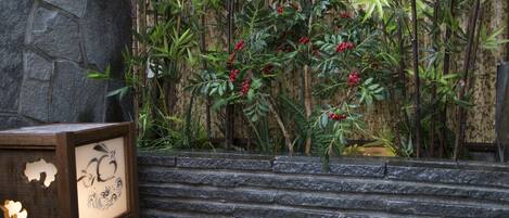 A stone wall with a bamboo plant and a wooden table with a black and white design.