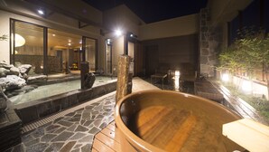 A modern spa area with a hot tub, stone flooring, and a glass-enclosed room with a view of the interior.