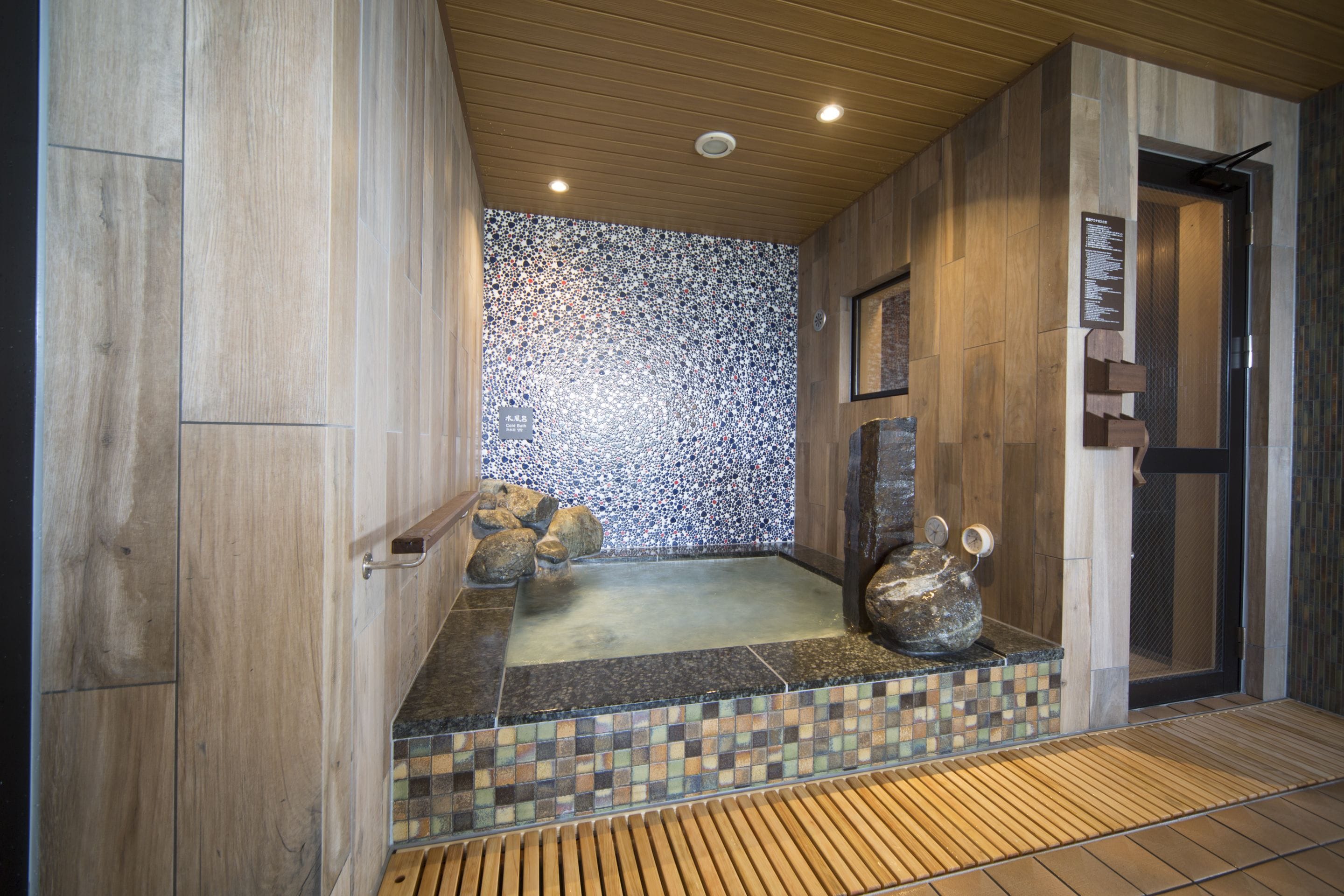 A spa area with a wooden floor, a stone wall, and a small hot tub.