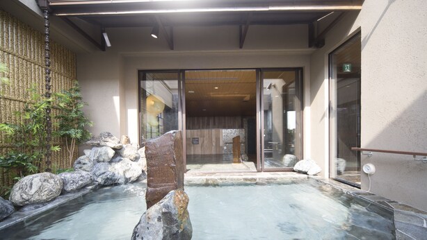 A stone-floored outdoor area with a small pool, rocks, and bamboo plants.