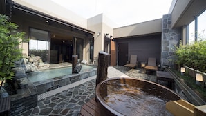 A modern outdoor spa area with a hot tub, stone flooring, and seating.