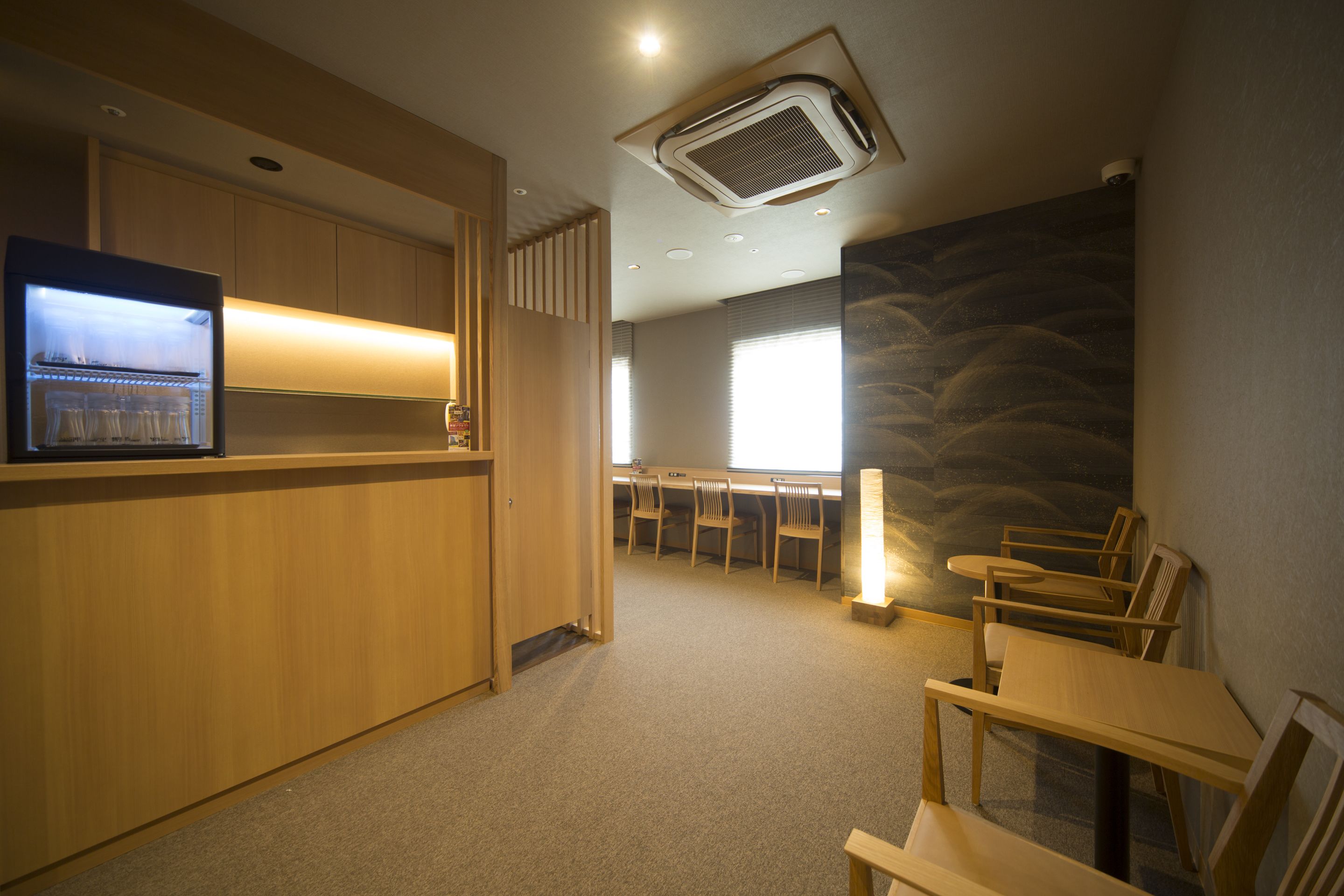 A hotel lobby with a reception desk, seating area, and a large window providing natural light.