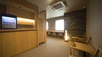 Un vestíbulo de hotel con mostrador de recepción, zona de estar y un amplio ventanal que proporciona luz natural.