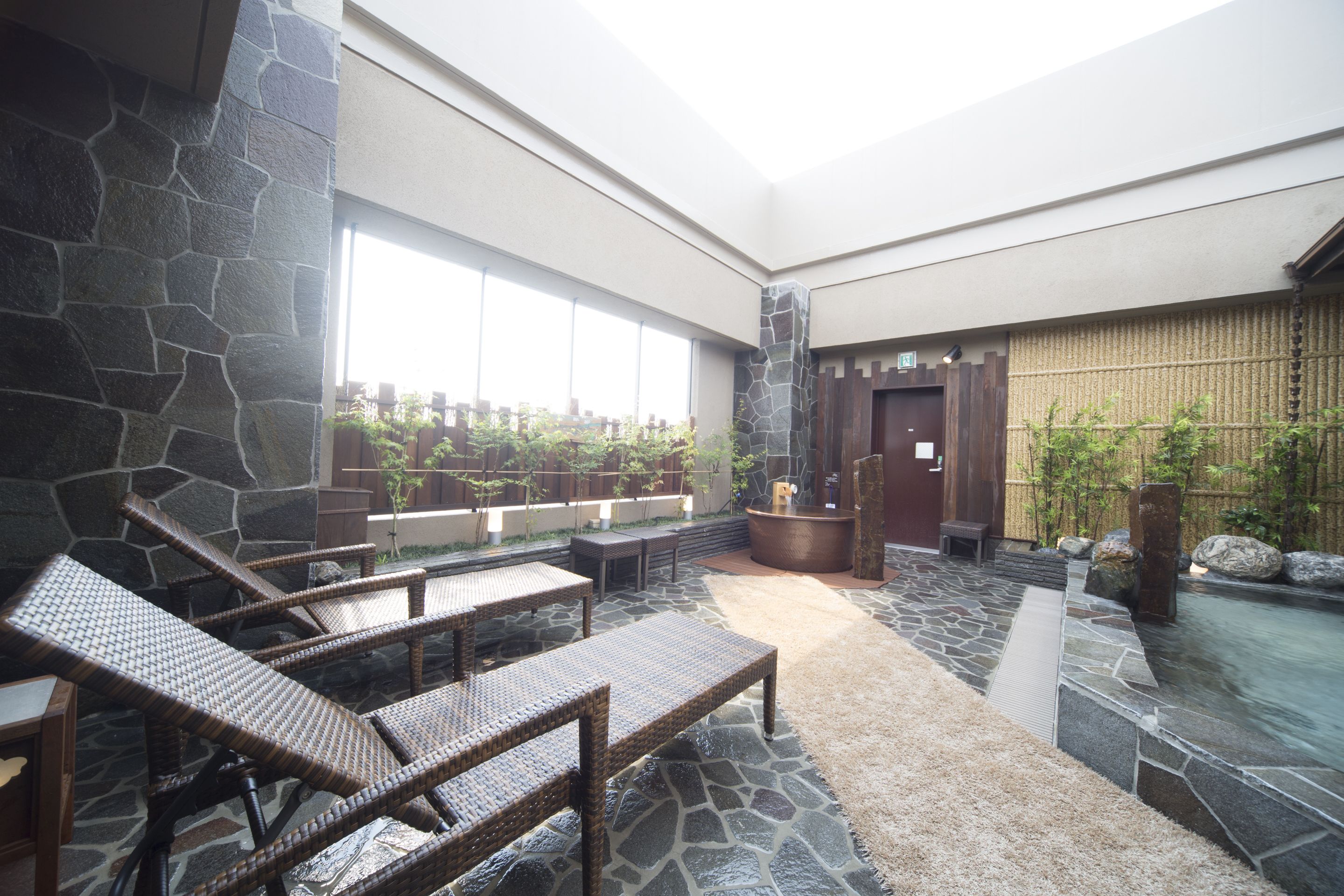 A spa area with stone walls, a hot tub, and wicker lounge chairs.