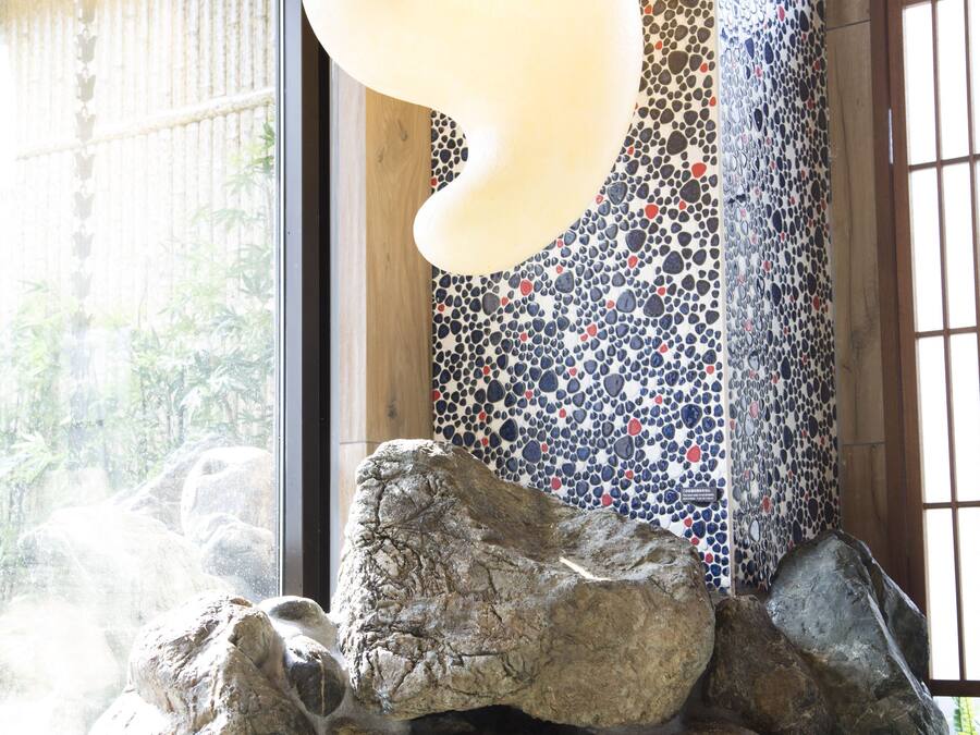 Eine Felsformation mit einem kleinen Wasserfall, einer Mosaikwand und einer hängenden Leuchte.