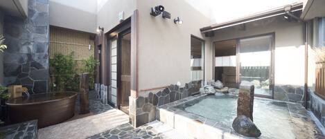 A spa area with a stone-tiled floor, a hot tub, and a small pool.