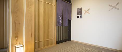 Un pasillo con una puerta de madera, una lámpara de pie iluminada y un cartel con caracteres japoneses.