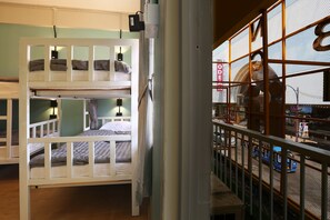 Quarto com beliche e vista para a rua através de uma janela de tela.
