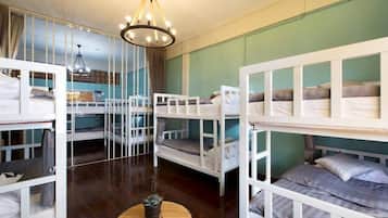 A room with bunk beds, a round wooden table, and a chandelier.