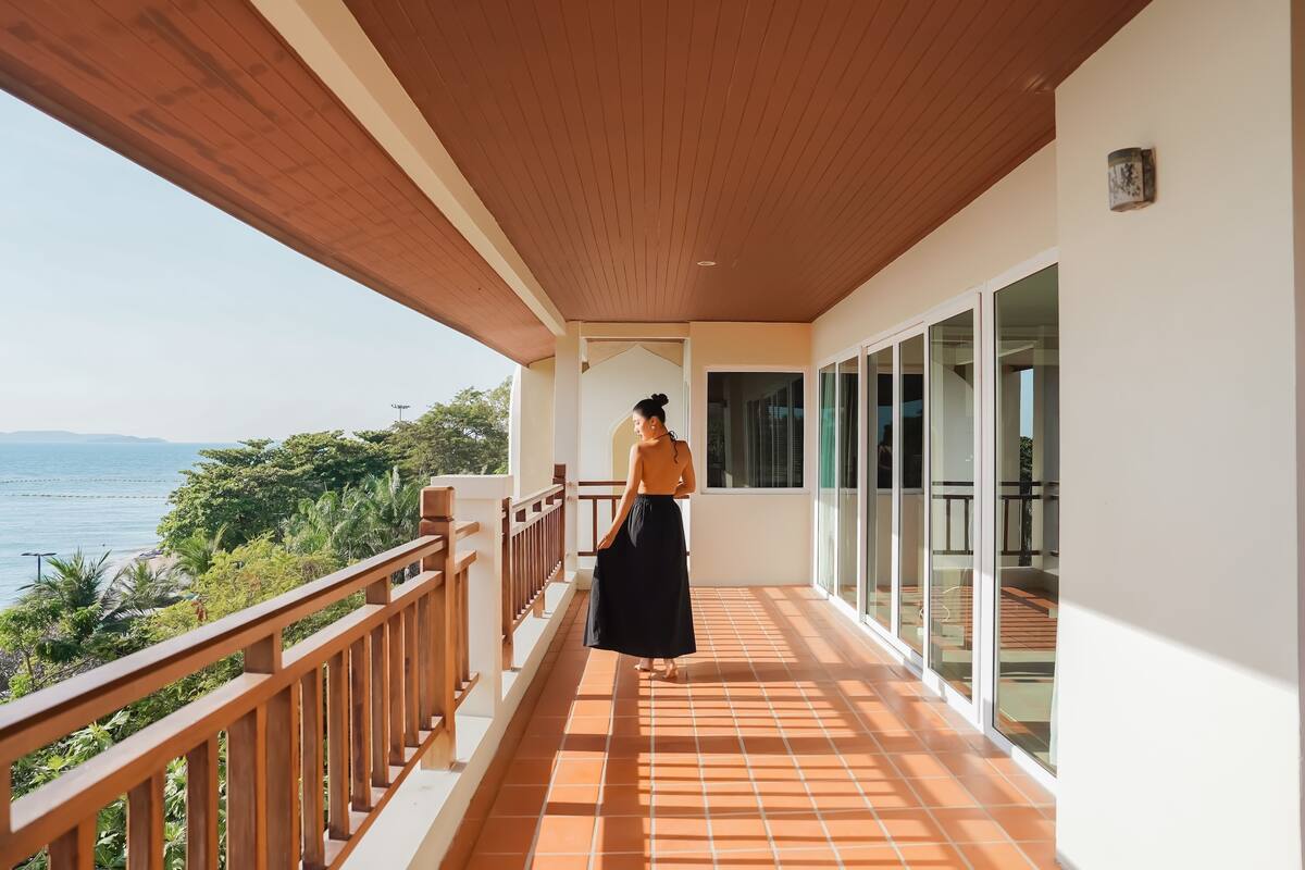 Un balcon avec vue sur la mer, des balustrades en bois et un sol carrelé.