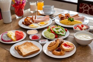 Un buffet de petit-déjeuner proposant divers plats, notamment des œufs, du bacon, des toasts et des viennoiseries.