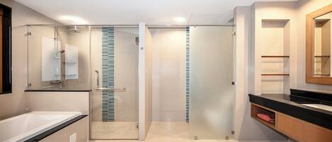 A modern bathroom with a glass-enclosed shower, a large bathtub, and a wooden vanity with a mirror.