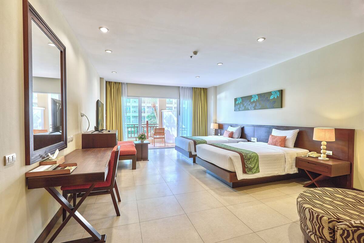 Une chambre d’hôtel avec un lit, un bureau, une chaise et un grand miroir.