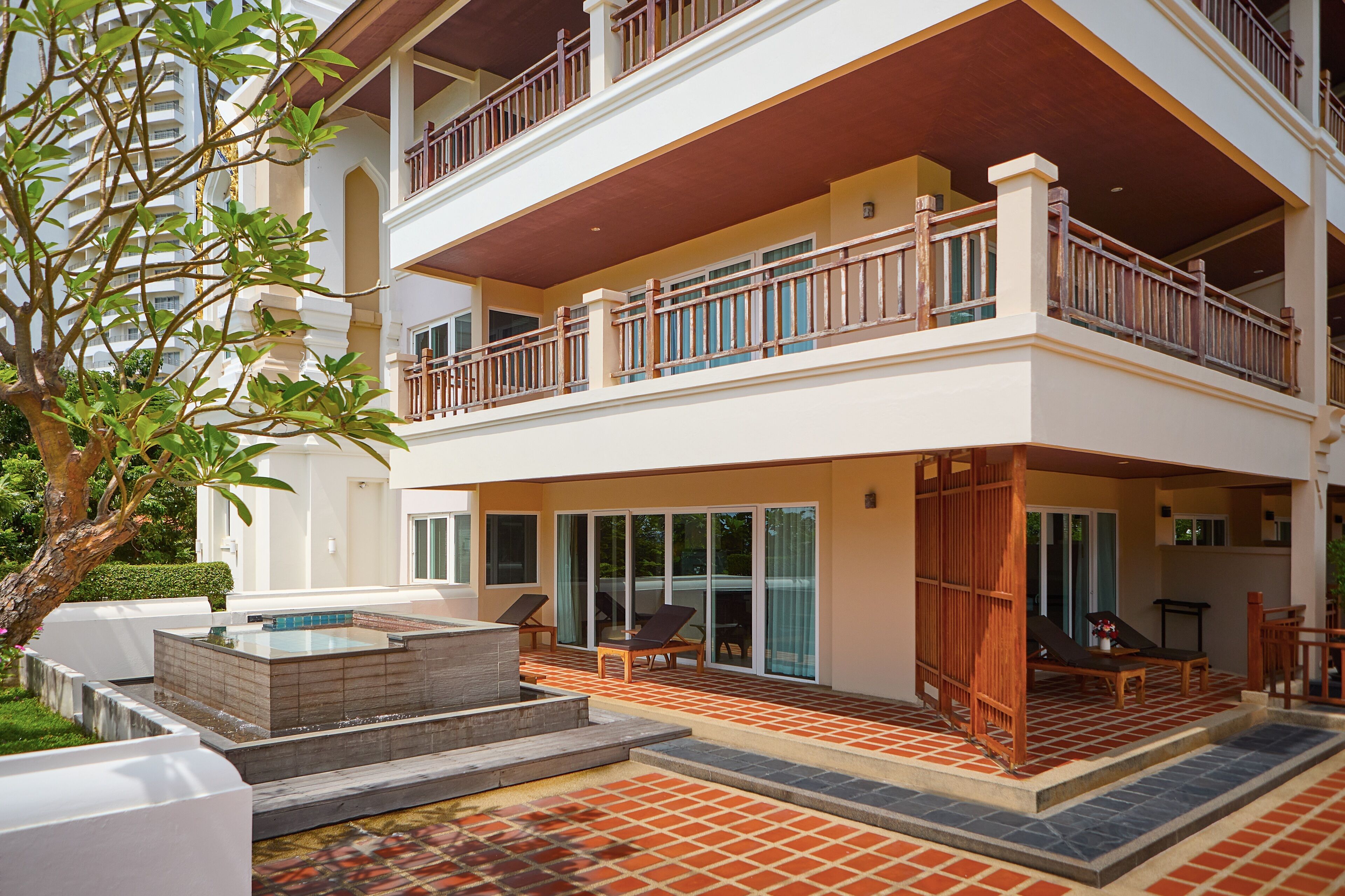 Un bâtiment à deux étages doté d’un balcon, d’un espace extérieur aménagé pour s’asseoir et d’une petite piscine.