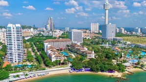 Un complejo turístico costero con varias edificaciones hoteleras, una torre destacada y una zona de playa con sombrillas.