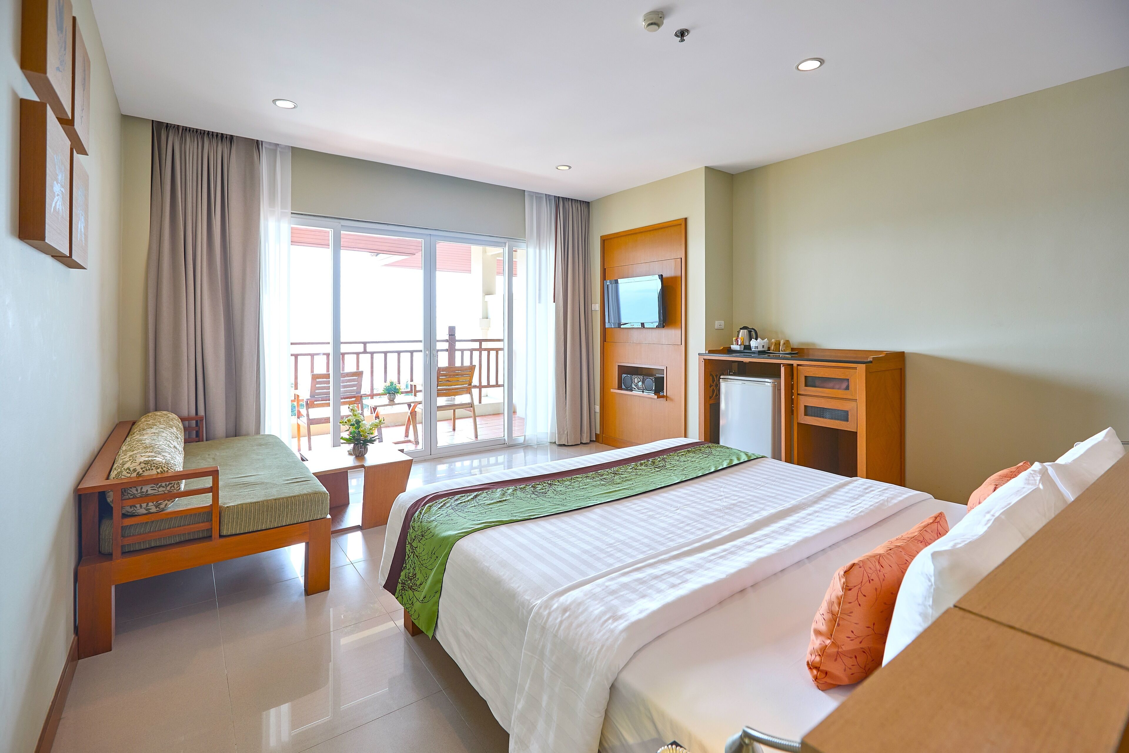 Ein Hotelzimmer mit Bett, Sofa, Schreibtisch, Fernseher und einem Balkon mit Aussicht.