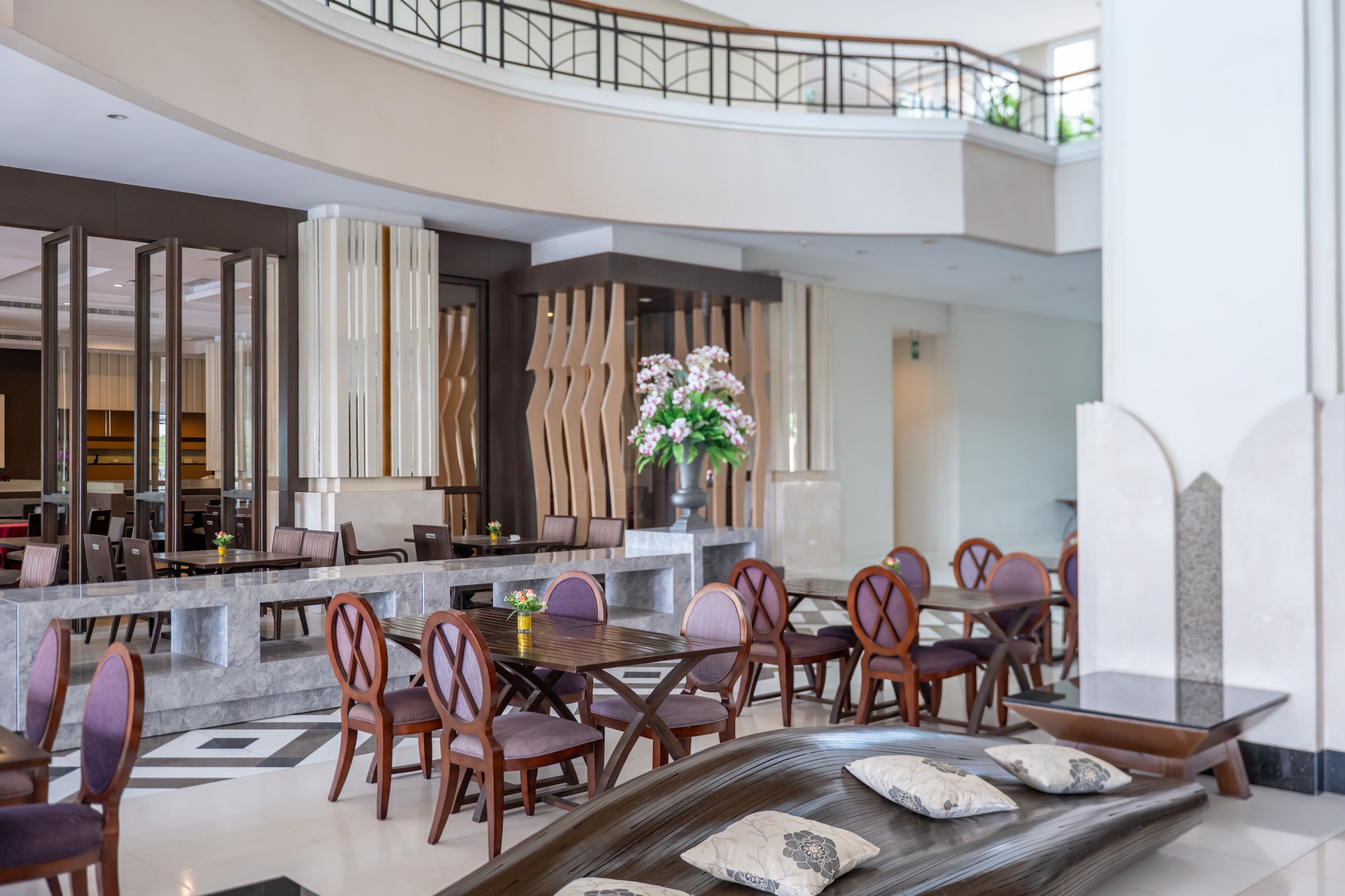 A spacious lobby with a central seating area, a high ceiling, and a view of the upper floor.