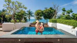 Una piscina con vistas al mar, rodeada de vegetación y una terraza de madera.