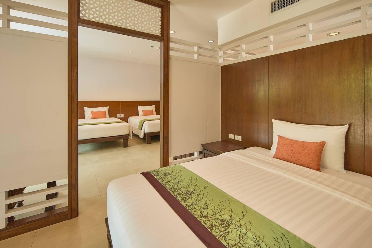 Une chambre d’hôtel avec un grand lit, une tête de lit en bois et un miroir qui reflète une autre pièce.