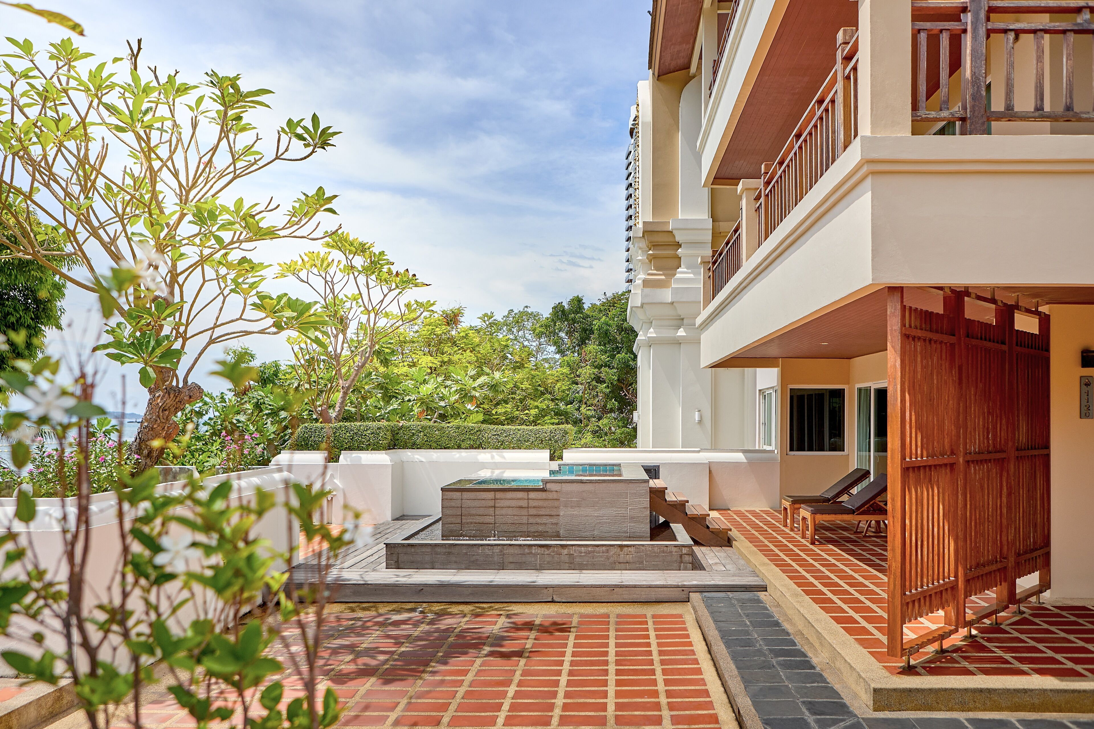 Un patio de hotel con piscina, zona de estar y vistas al entorno verde.