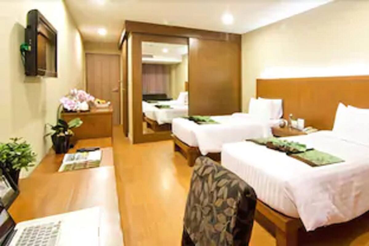 A hotel room with two beds, a desk with a laptop, and a chair.