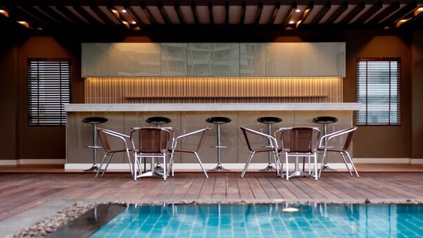 A modern indoor pool area with a bar and seating. - The Stay Hotel (Pattaya)