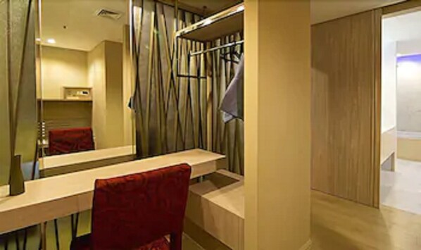 A modern bathroom with a large mirror, a wooden vanity, and a red chair. - The Stay Hotel (Pattaya)
