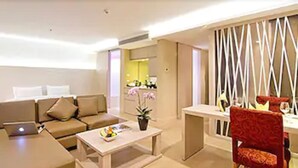A modern living room with a sofa, a coffee table, and a dining area with a chair. - The Stay Hotel (Pattaya)
