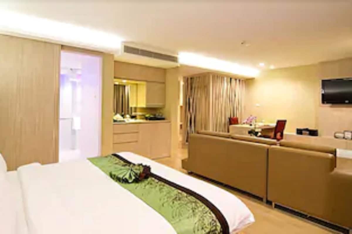 A hotel room with a bed, a desk, and a kitchenette.