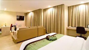 A hotel room with a bed, a sofa, a desk, and a TV. - The Stay Hotel (Pattaya)