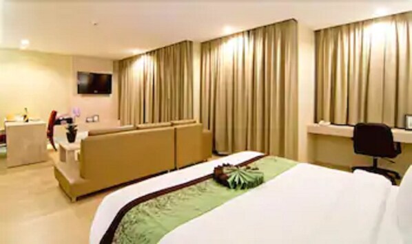 Une chambre d’hôtel avec un lit, un canapé, un bureau et une télévision.