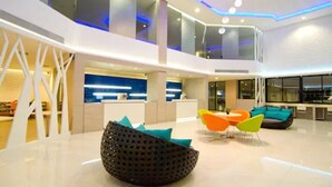 A spacious lobby with a high ceiling, modern seating, and a reception area. - The Stay Hotel (Pattaya)
