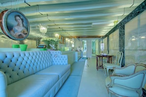 A modern interior with a white sofa, a dining table with chairs, and a large mirror.