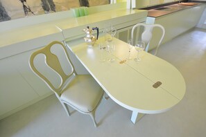 A dining area with a white table and chairs, a pitcher, glasses, and a small decorative item. - GranDELUX-Canal (Venice)