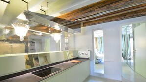 A modern kitchen with a stainless steel countertop, a built-in oven, and a wooden ceiling. - GranDELUX-Canal (Venice)