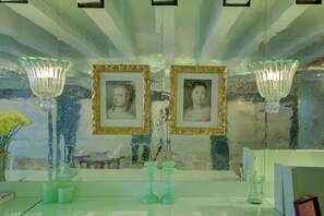 A bathroom with a mirror, two framed pictures, and two green candle holders. - GranDELUX-Canal (Venice)