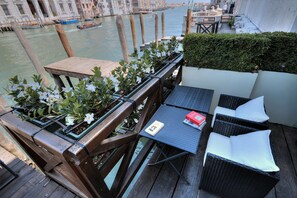 A wooden deck with outdoor furniture, a small table with a book, and potted plants. - GranDELUX-Canal (Venice)