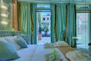 A hotel room with a large bed, a view of the courtyard, and a mirror. - GranDELUX-Canal (Venice)