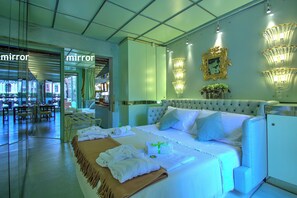 A hotel room with a large bed, a seating area with tables and chairs, and a view of the outside.