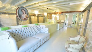 A spacious lobby with a white sofa, a classic armchair, and a reception desk. - GranDELUX-Canal (Venice)