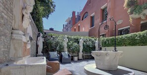 Un patio privé agrémenté de jardinières en pierre, de sculptures classiques et d’une fontaine.
