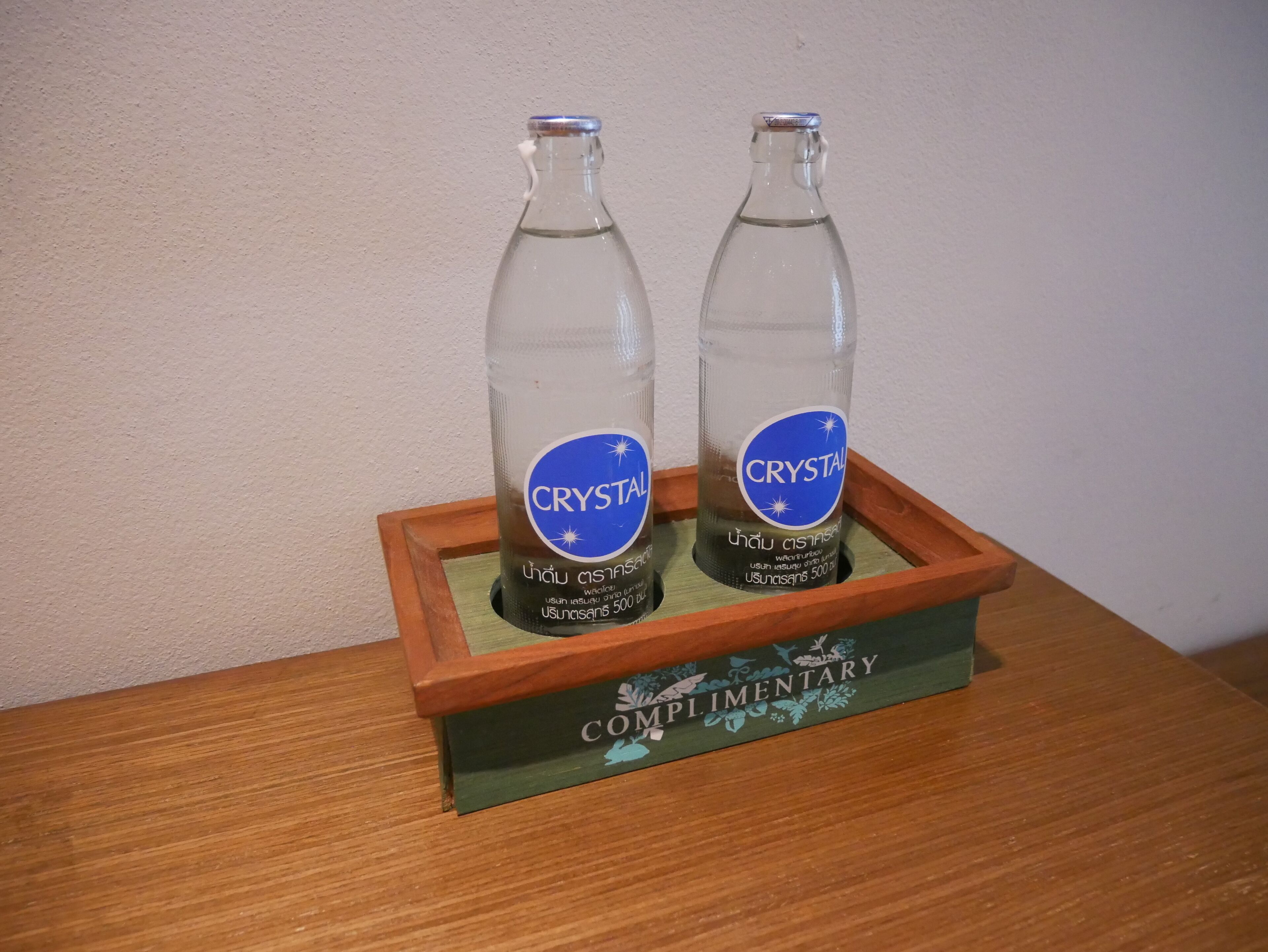Twee flessen Crystal water in een houten doos met een etiket waarop staat 'Gratis'.