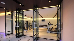 A gym with exercise equipment, glass doors, and a patterned floor. - Season Five Hotel (Pattaya)