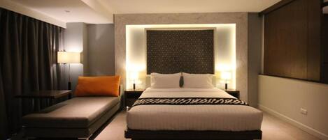 A modern hotel room with a large bed, a sofa, and a desk.