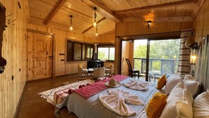 Una cabaña de madera acogedora con una cama grande, una chimenea y un balcón con vistas al exterior.