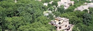 A modern building with a flat roof, surrounded by dense green trees.