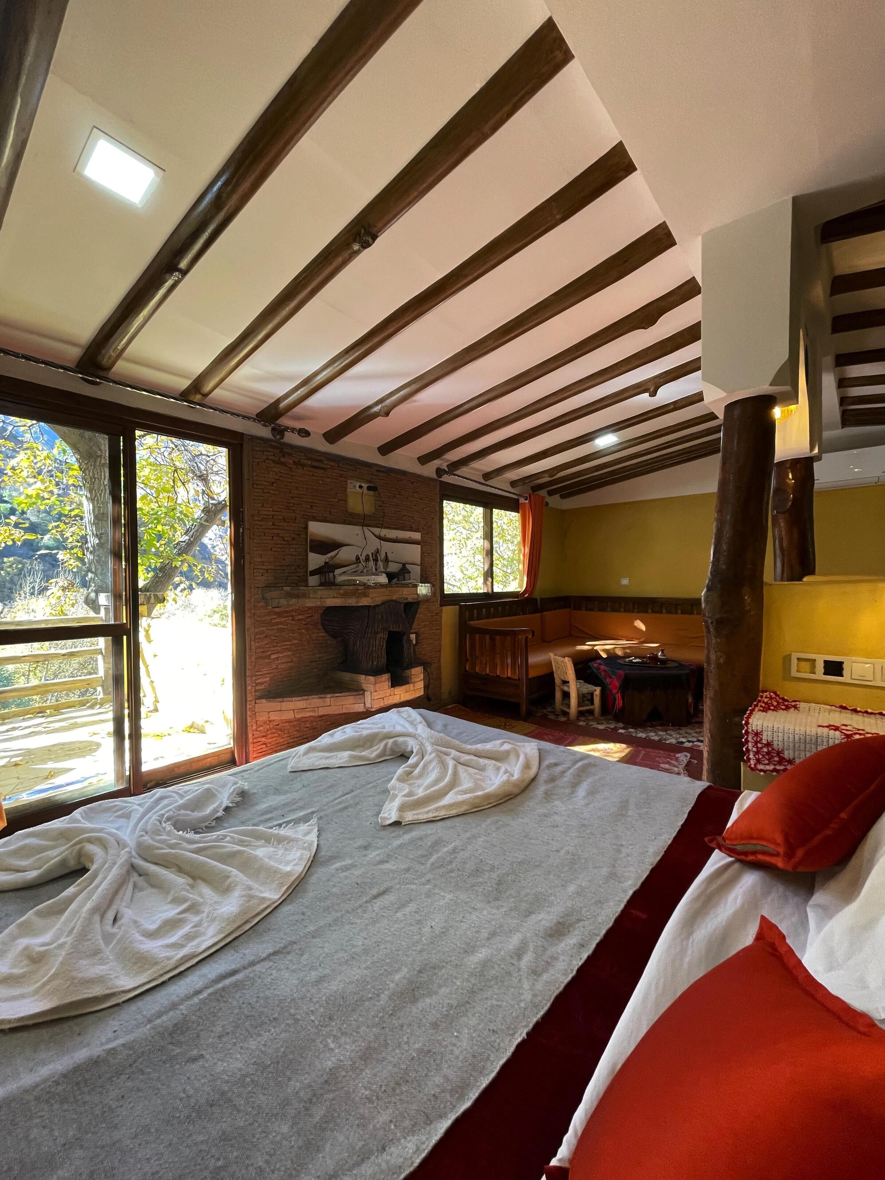 A room with a bed, a fireplace, a window, and a view of the outdoors.