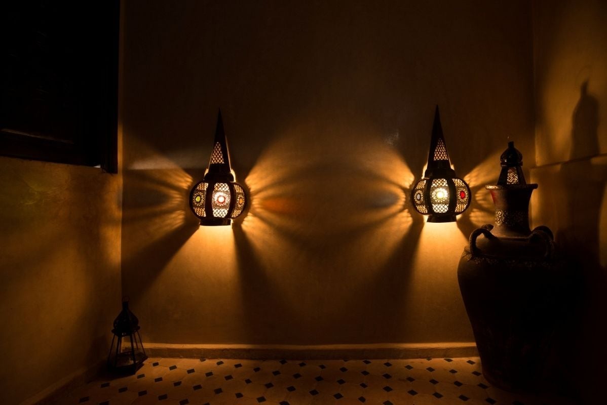 Deux lanternes fixées au mur, éclairant un mur.