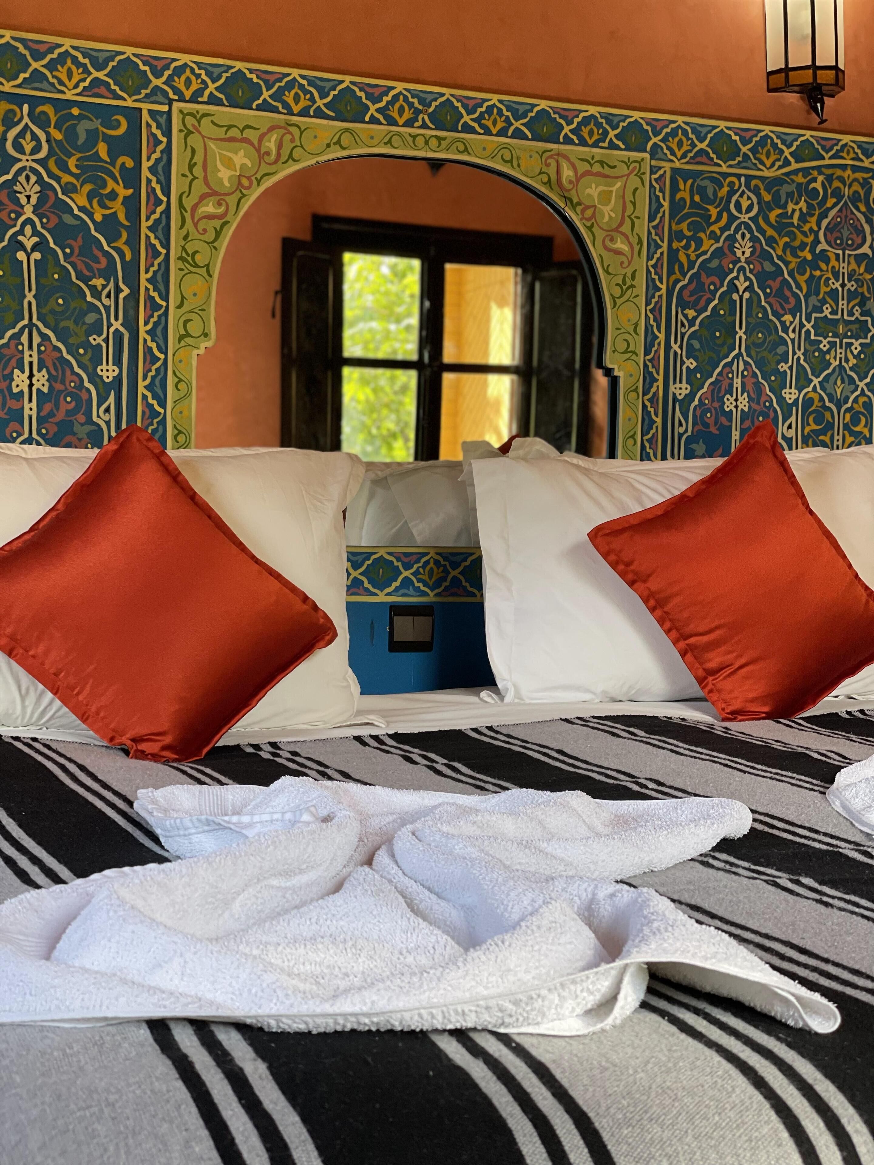 Una habitación de hotel con una cama, almohadas blancas y una alfombra a rayas.